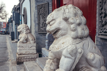 Fototapeta na wymiar Lion sculptures in front of a house entrance in alley called hutong - traditional residential area in Beijing, capital city of China