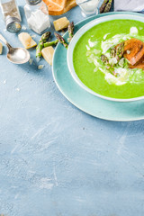 Healthy homemade asparagus vegetable cream soup in a bowl on light blue slate, stone or concrete background. Copy space.