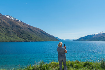 Fototapeta na wymiar Woman on the background of lake Wakatipu, Queenstown, New Zealand. Copy space for text. Back view.
