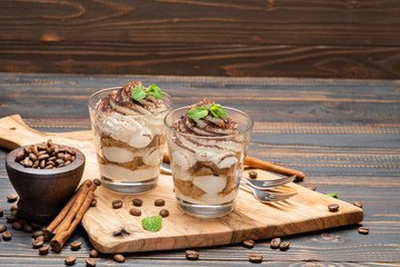 Classic tiramisu dessert in a glass on wooden background