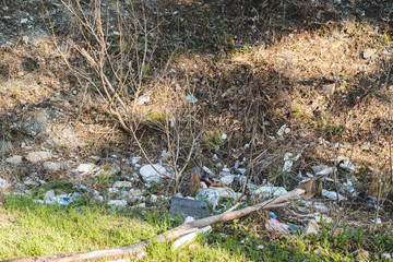 Ecological concept. Ecology problems of the planet Earth. Rubbish in places of rest by the sea. Plastic bottles among green grass and flowers.