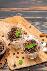 Classic tiramisu dessert in a glass on wooden background
