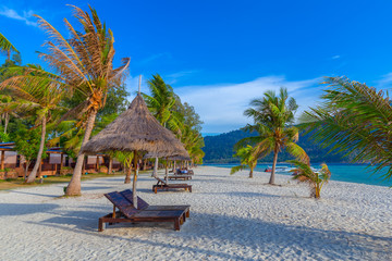 Beach chairs, umbrella and palms on the beautiful beach for holidays and relaxation at Koh Lipe island, Thailand