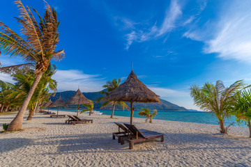 Beach chairs, umbrella and palms on the beautiful beach for holidays and relaxation at Koh Lipe island, Thailand