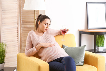 Pregnant woman drinking wine at home