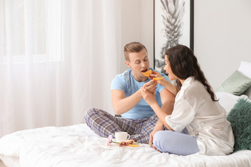 Cute young couple having breakfast in bed