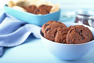 Bowl with tasty chocolate cookies on wooden table