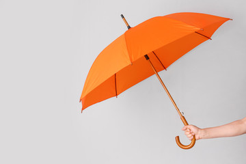 Female hand with umbrella on light background