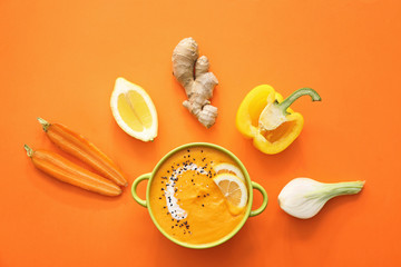 Pot of tasty cream soup and ingredients on color background