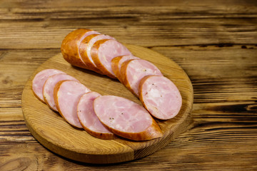 Sliced smoked sausage on cutting board on wooden table