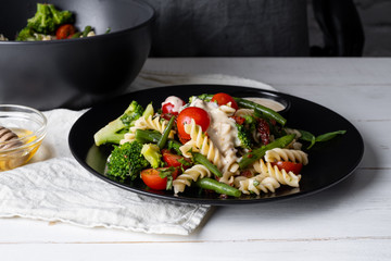 Chef cooking pasta with vegetables - traditional Italian salad dish,