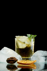 Chilled alcoholic cocktail with ice orange and fresh herbs on black background