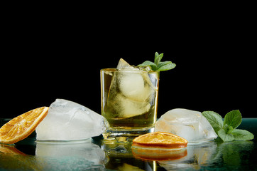 Chilled alcoholic cocktail with ice orange and fresh herbs on black background