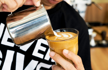 Barista is decorating latte coffee.