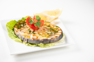 Grilled wordfish with salad and lemon on the white plate