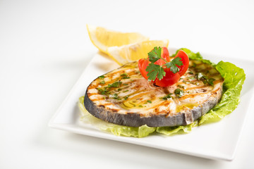 Grilled wordfish with salad and lemon on the white plate