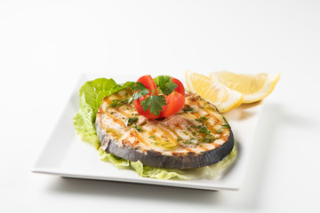 Grilled wordfish with salad and lemon on the white plate