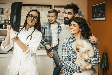 Happy family with their pomeranian dog at veterinary.