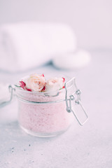 Spa and body care products. Aromatic rose bath Sea Salt, towel, candle on the grey background. Beauty skin care. Spa treatment