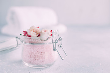 Spa and body care products. Aromatic rose bath Sea Salt, towel, candle on the grey background. Beauty skin care. Spa treatment