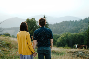 Back view Couple travelers. Man and woman looking on mountains and clouds. Love and travel, happy emotions. Lifestyle concept.