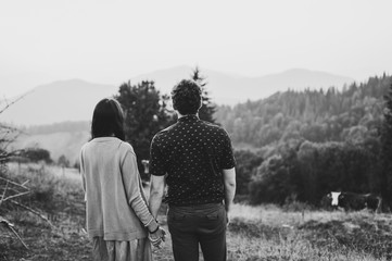 Back view Couple travelers. Man and woman looking on mountains and clouds. Love and travel. Lifestyle concept. Black and white photo.