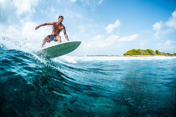 Young surfer with lean muscular body rides the tropical wave - obrazy, fototapety, plakaty