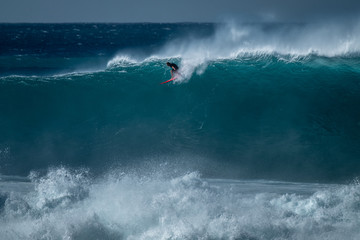 Surfer rides giant wave at the famous Waimea Bay surf spot located on the North Shore of Oahu in...