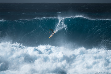 Surfer rides giant wave at the famous Waimea Bay surf spot located on the North Shore of Oahu in...