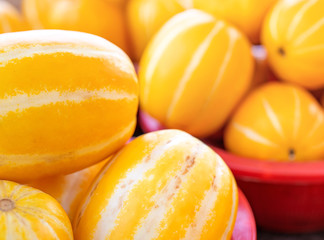 Delicious korean stripe yellow melon fruit food in red plastic basket at tradition market afternoon, Seoul, South Korea, harvest concept, close up.