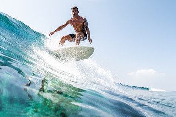 Young hispanic man surfs the glassy ocean wave at sunny day - obrazy, fototapety, plakaty