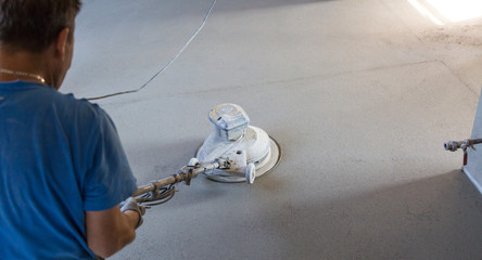 Laborer performing and polishing sand and cement screed floor. Sand and cement floor screed.