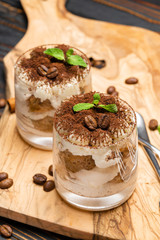 Classic tiramisu dessert in a glass on wooden background