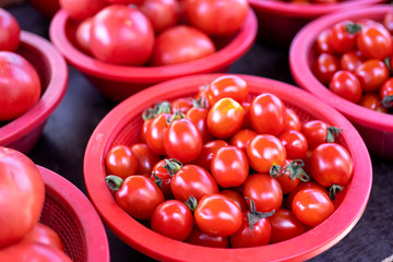 Delicious fresh tomatoes fruit vegetable food in red plastic basket at tradition market afternoon, Seoul, South Korea, harvest concept, close up.