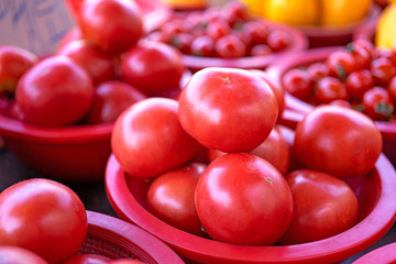 Delicious fresh tomatoes fruit vegetable food in red plastic basket at tradition market afternoon, Seoul, South Korea, harvest concept, close up.