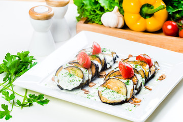 Grilled slices of eggplant and tomatoes in stack with spicy sauce