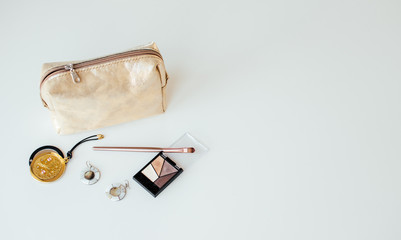 Golden cosmetic bag with cosmetic beauty products.