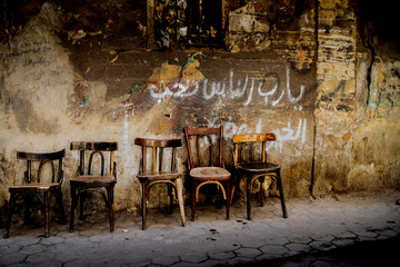 Timeworn chairs in front of a wall drawing on Cairo's streets