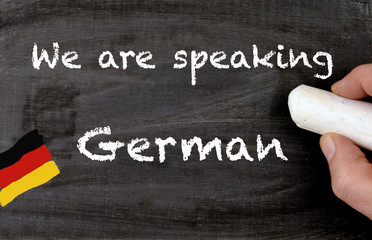 Hand writing we are speaking german on a chalkboard