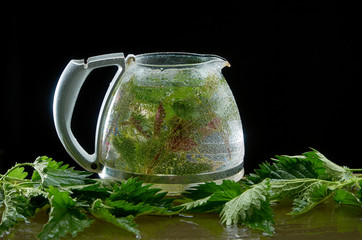 The pot of tea from medicinal nettle with on a black background