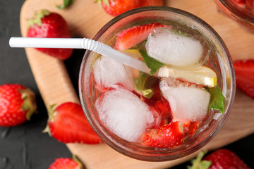 Strawberry Mojito. Cold summer mojito cocktail with strawberries, mint, lemon and ice in a glass on a black table. summer refreshing drink. top view