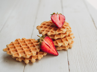 Belgian Waffles with fresh strawberry. Closeup on white wood