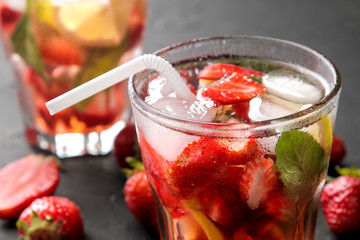 Strawberry Mojito. Cold summer mojito cocktail with strawberries, mint, lemon and ice in a glass on a black table. close-up
