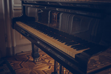 Fototapeta na wymiar A black classic grand piano stands in a luxury room. classical musical instrument close up, baroque interior
