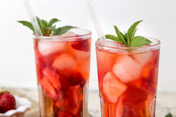 Strawberry Mojito. Cold summer mojito cocktail with strawberries, mint, lemon and ice in a glass on a natural wooden table. A refreshing summer drink. close-up