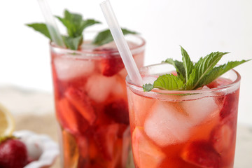 Strawberry Mojito. Cold summer mojito cocktail with strawberries, mint, lemon and ice in a glass on a natural wooden table. A refreshing summer drink. close-up