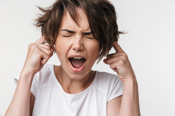 Pretty displeased stressed woman posing isolated over white wall background covering ears because of loud.