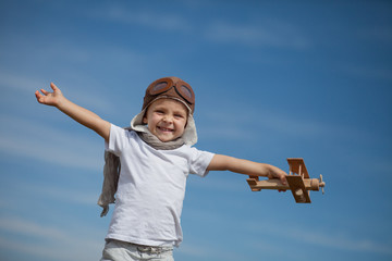 Child playing with wooden airplane toy, boy imagines discovery adventure