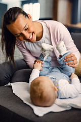 Happy mother having fun with her baby boy on the sofa.