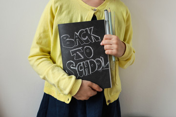 The child is holding a notebook with an inscription back to school